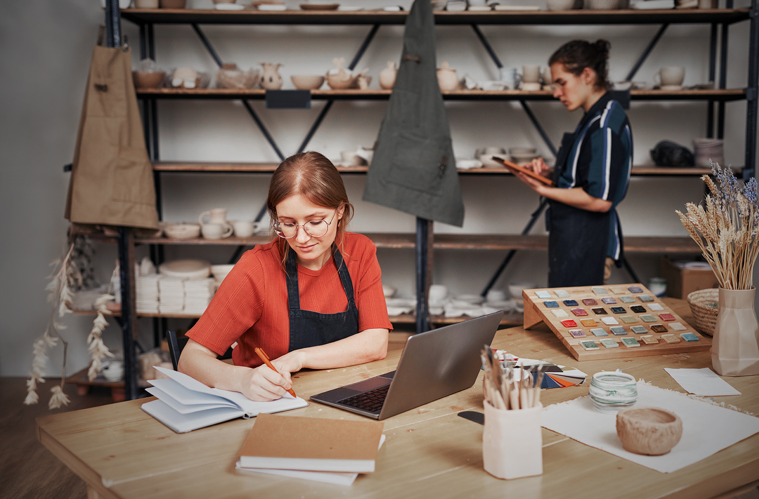 The owner of a ceramics studio issues invoices on her laptop—what is online factoring?