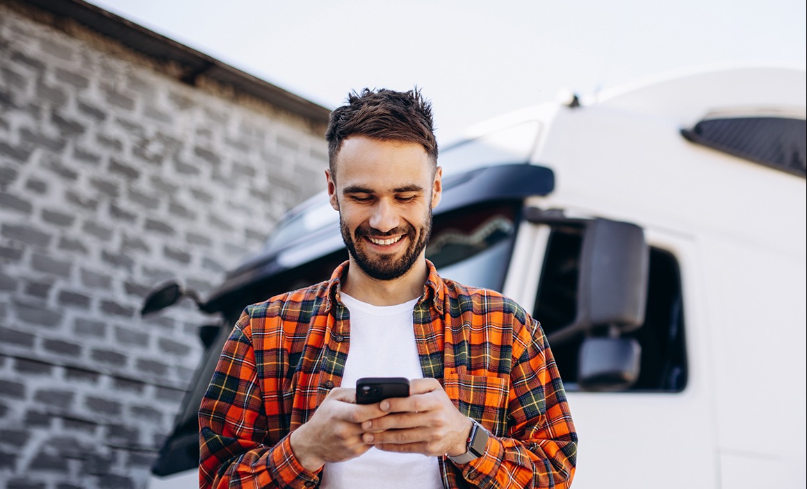 właściciel firmy transportowej ze smartfonem przy ciężarówce – historia klienta faktoringu online