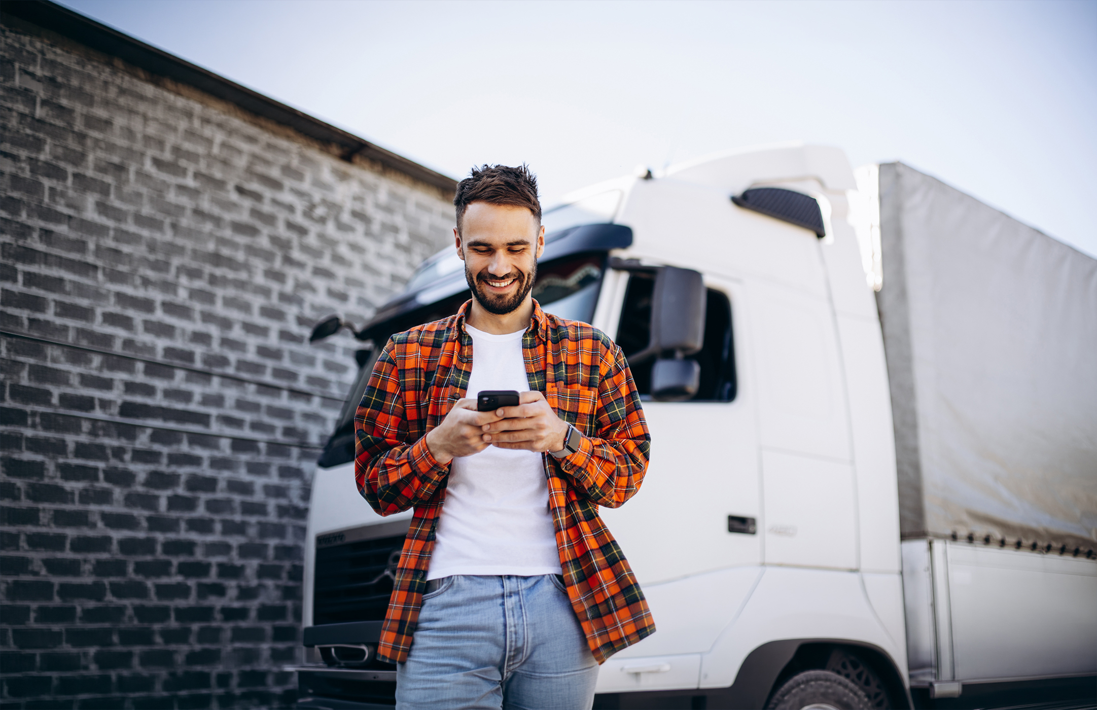 przedsiębiorca z branży transportowej obsługuje finansowanie faktur w telefonie przy swojej ciężarówce