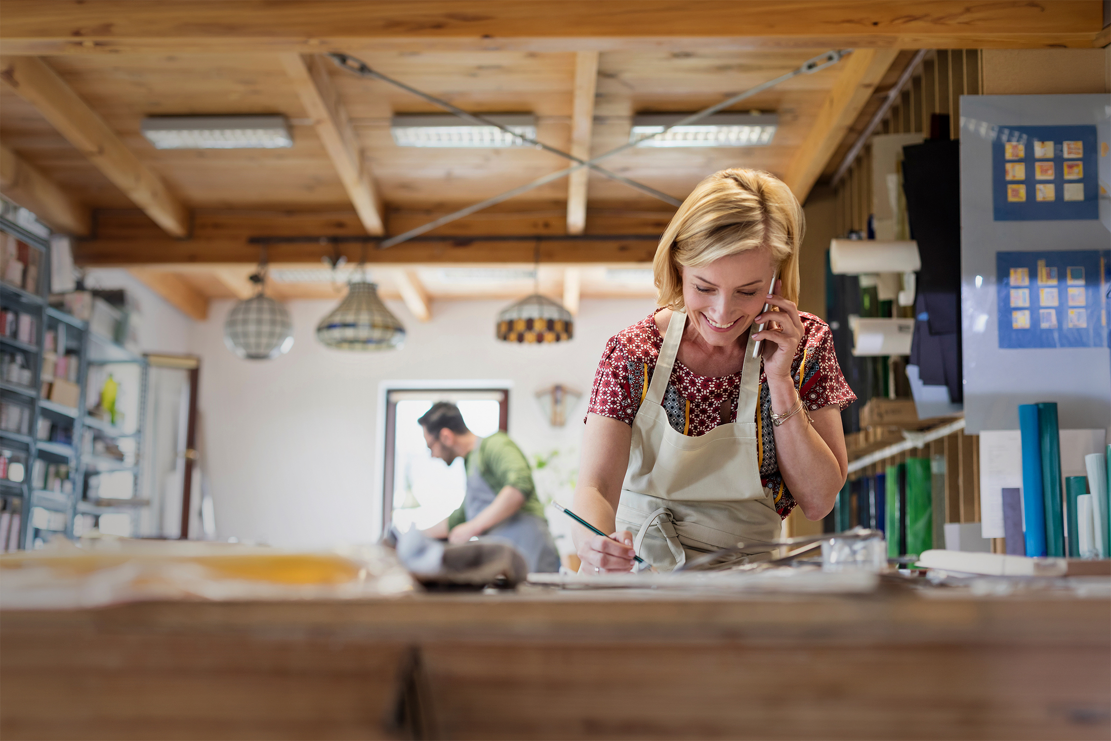The owner of a craft workshop is on the phone discussing financing for company purchases