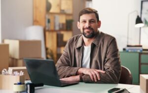 przedsiębiorca w magazynie siedzi przy komputerze i analizuje aktywa obrotowe firmy