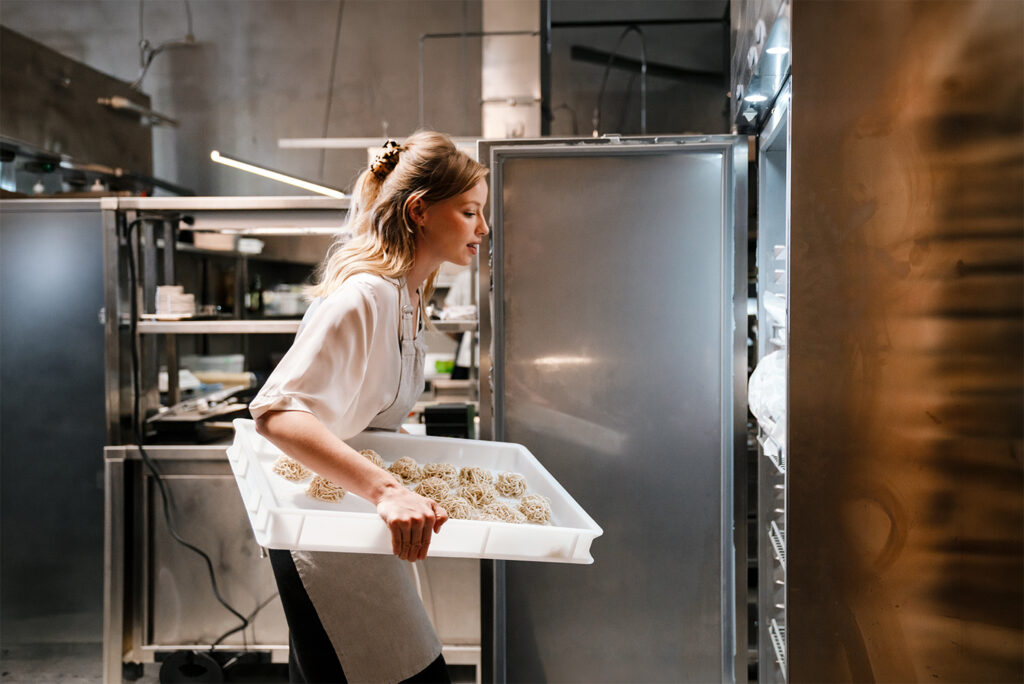 Właścicielka restauracji z tacą wypieków w kuchni – pożyczka dla firm PragmaCash